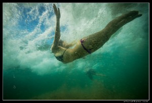 Woman in bikini diving under a wave