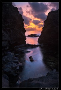 Intense sunset color as seen between two rocks along the north shore of Kauai
