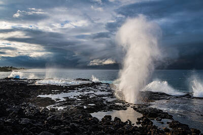 Fine art photograph of volcanic ocean blowhole, Spouting Horn, erupting with explosive spray with storm cloud behind at Poipu, Kauai, Hawaii