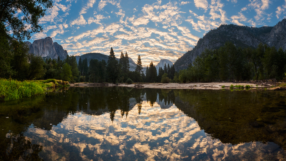 Sunrise in Yosemite with Half Dome, El Capitan, and clouds reflected in water below