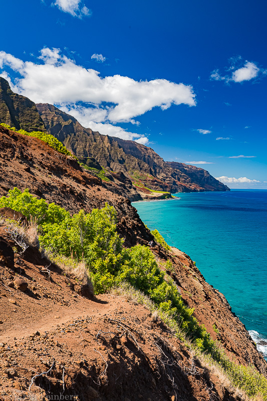 Hiking the Kalalau Trail along the Na Pali Coast with vibrant turquoise waters.